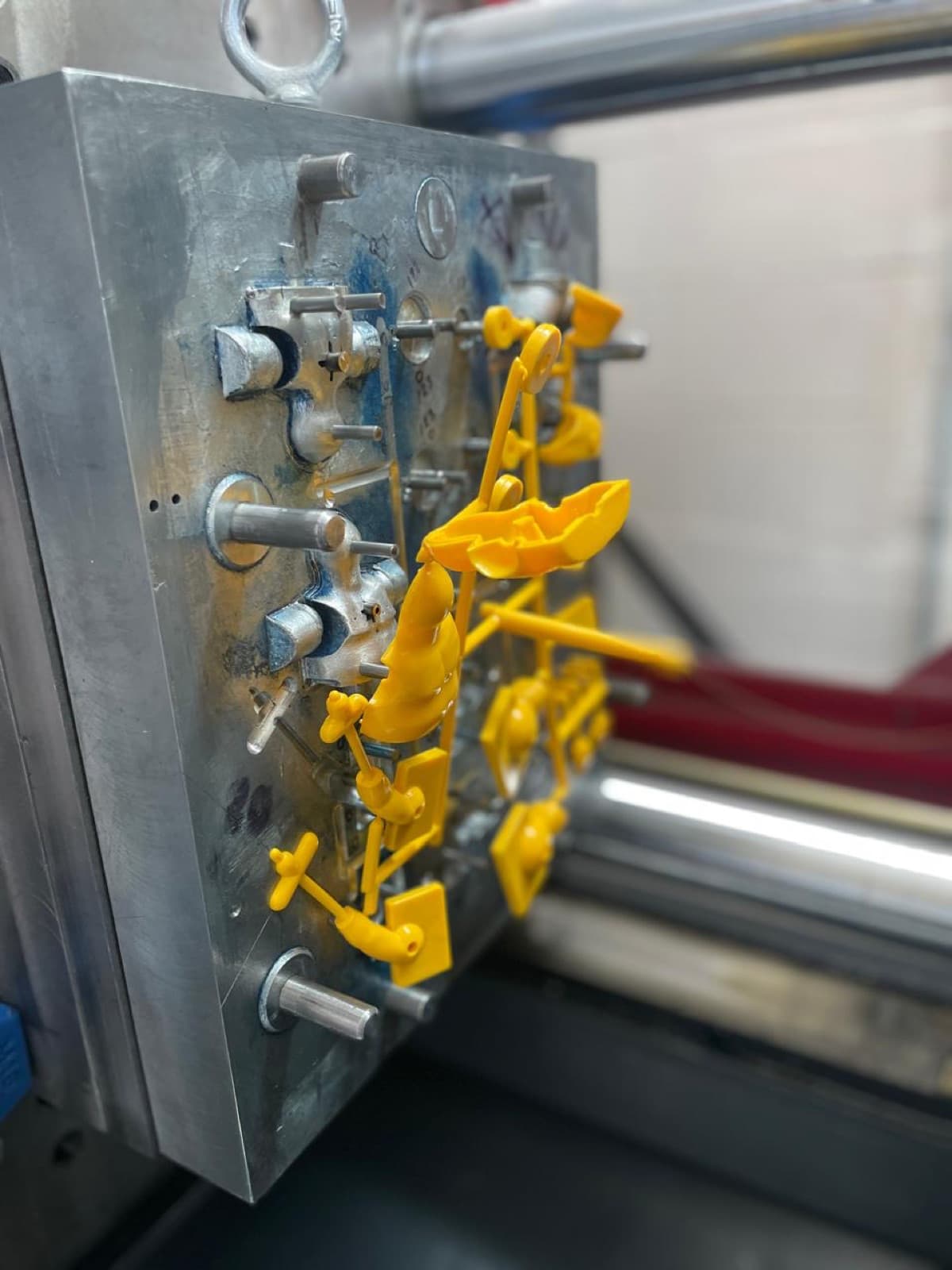 Molde de inyección abierto en máquina con piezas de plástico amarillo recién inyectadas en el árbol